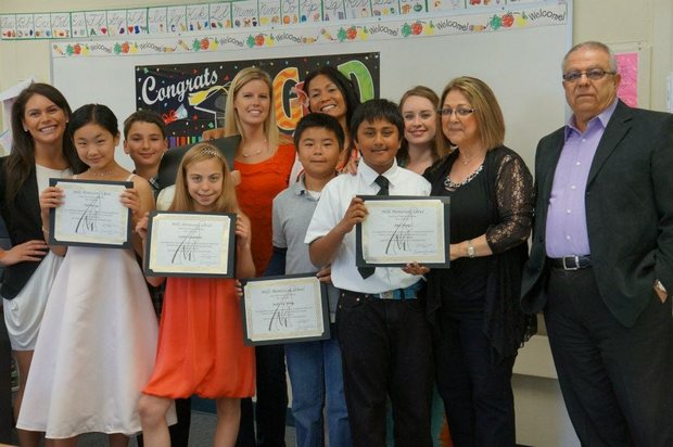 A Mills Montessori graduating class holding their school certificates