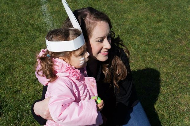 A Mills Montessori teacher crouching beside a child on the school field